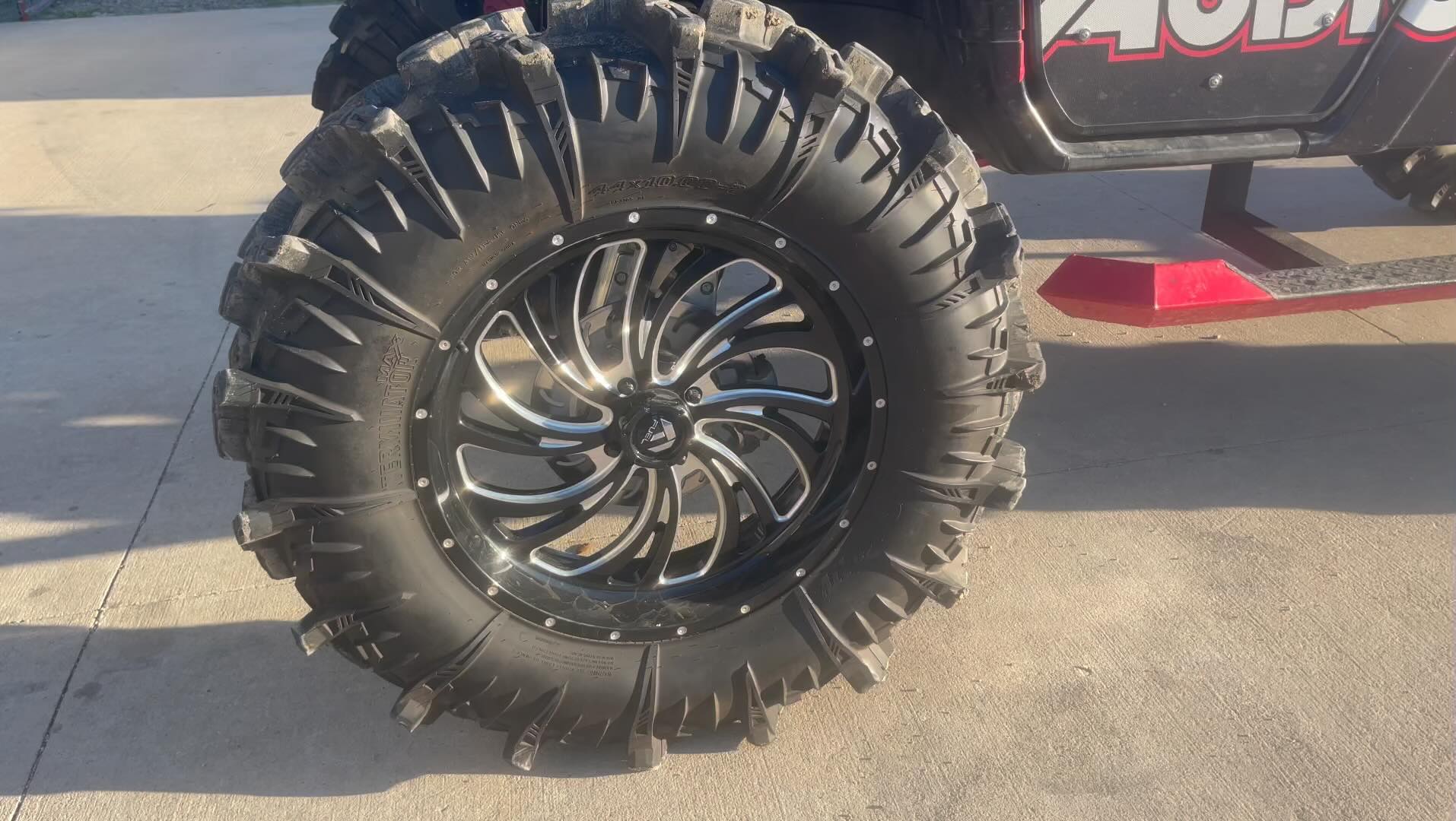 Machined black multi-spoke ATV wheel with aggressive mud terrain tire