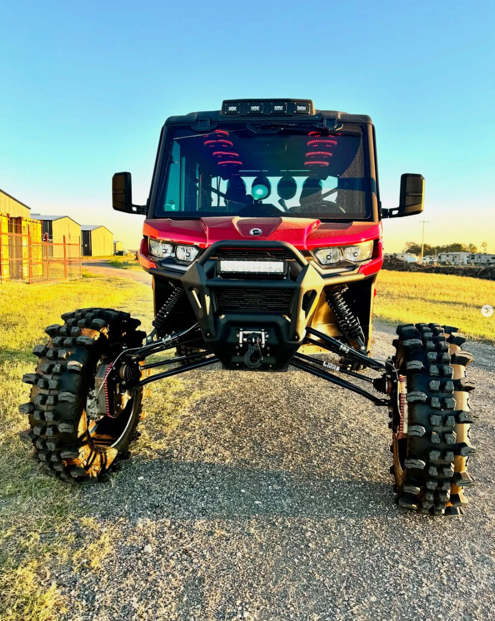 Red Can-Am UTV with front wheels removed showcasing custom long-travel suspension system with red coilovers