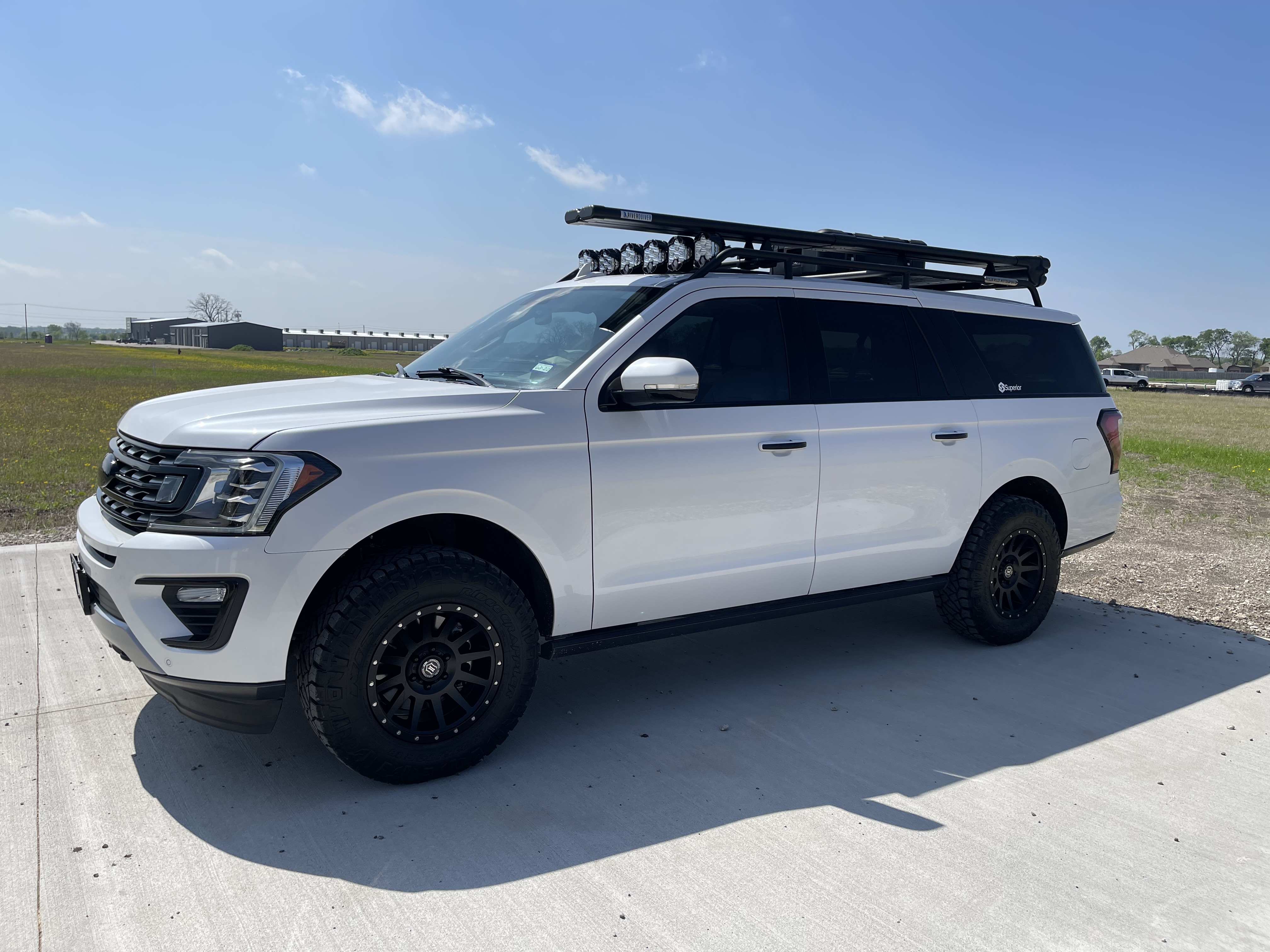 White Ford Expedition with custom roof rack, LED lighting, and lifted suspension